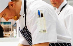 Two individual wearing stripped aprons and white chef uniforms
