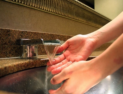 A person washing her hands with running water