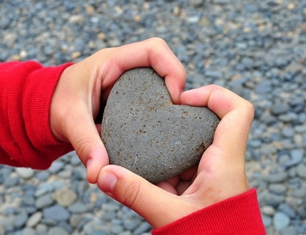 Two hands holding a heart formed stone