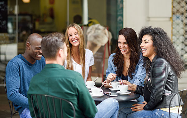 happy group of young adult talking in a cafe