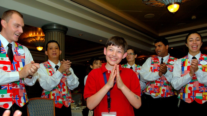young boy surrounded by cheerful restaurant staff