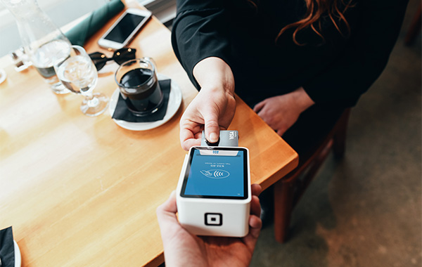 different person holding a terminal and credit card