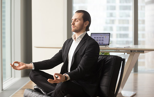 male employee performing yoga inside the office