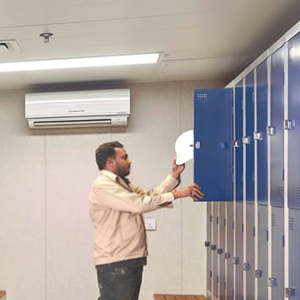 man placing a white hard hat in a blue locker