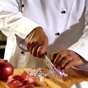 chef wearing white uniform cutting onions